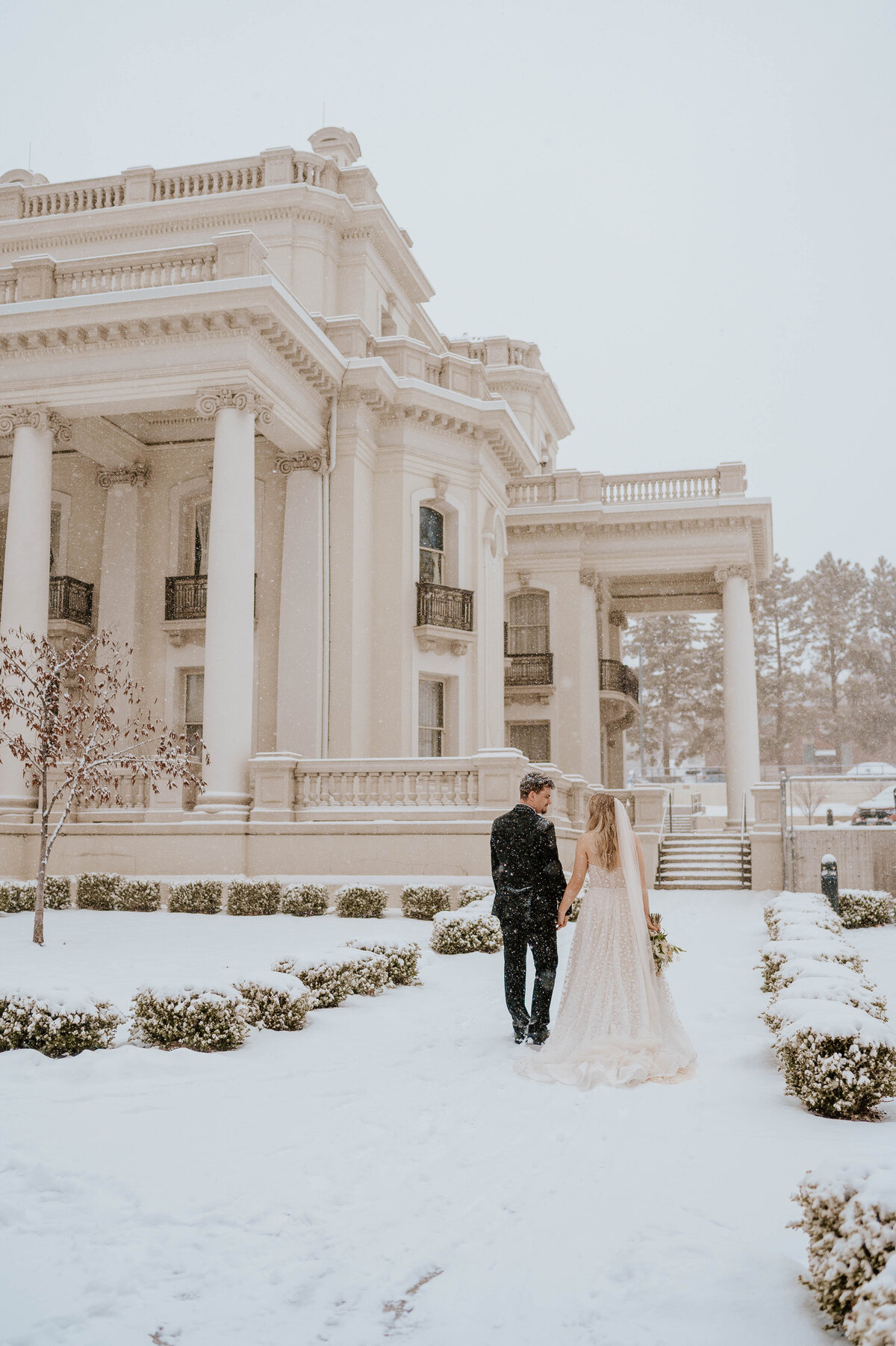 Classy outdoor winter wedding photo of bride and grrom walking away holding hands