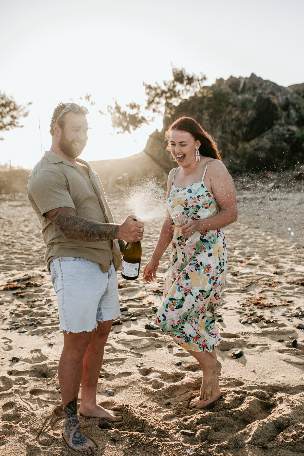 Documentary style wedding photography of a couple celebrating and popping a bottle of champagne on the beach!