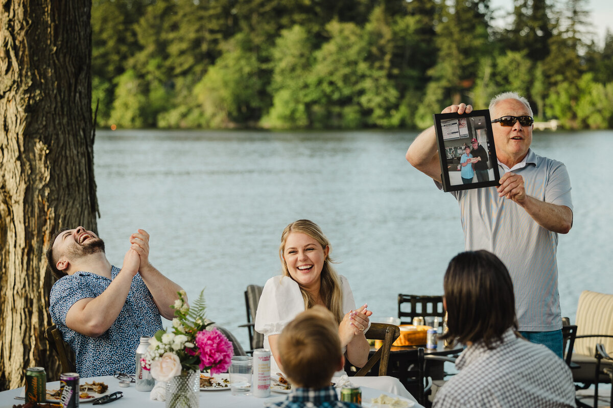 A couple sits at a table near the lake at their rehearsal dinner.