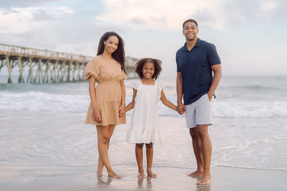 Mom and dad holding hands with their baby girl during a portrait session in Myrtle Beach, SC