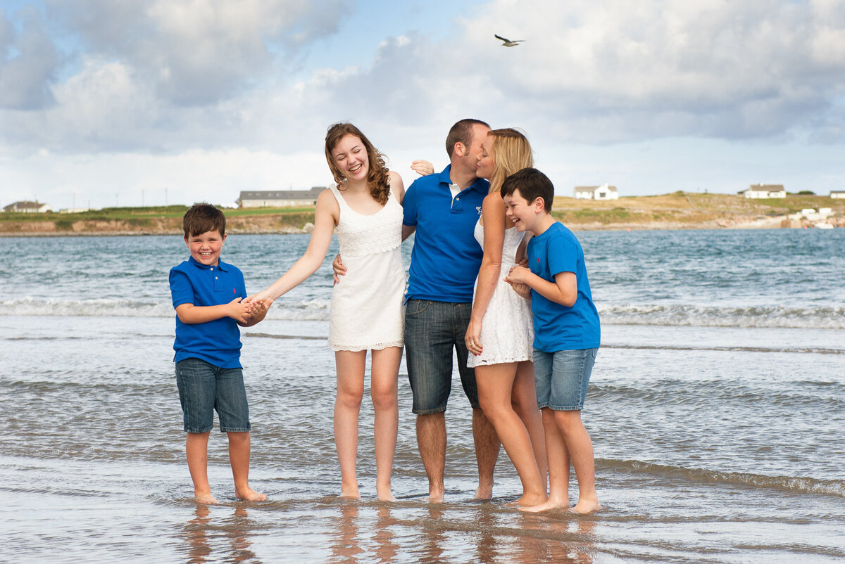 summer portrait on the beach of a family of five wearing blue, white and denim and having fun