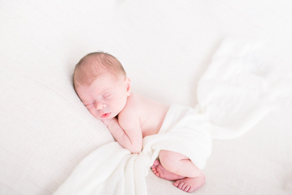 Baby boy laying with wrap laid across his back. Captured by Niagara newborn photographer