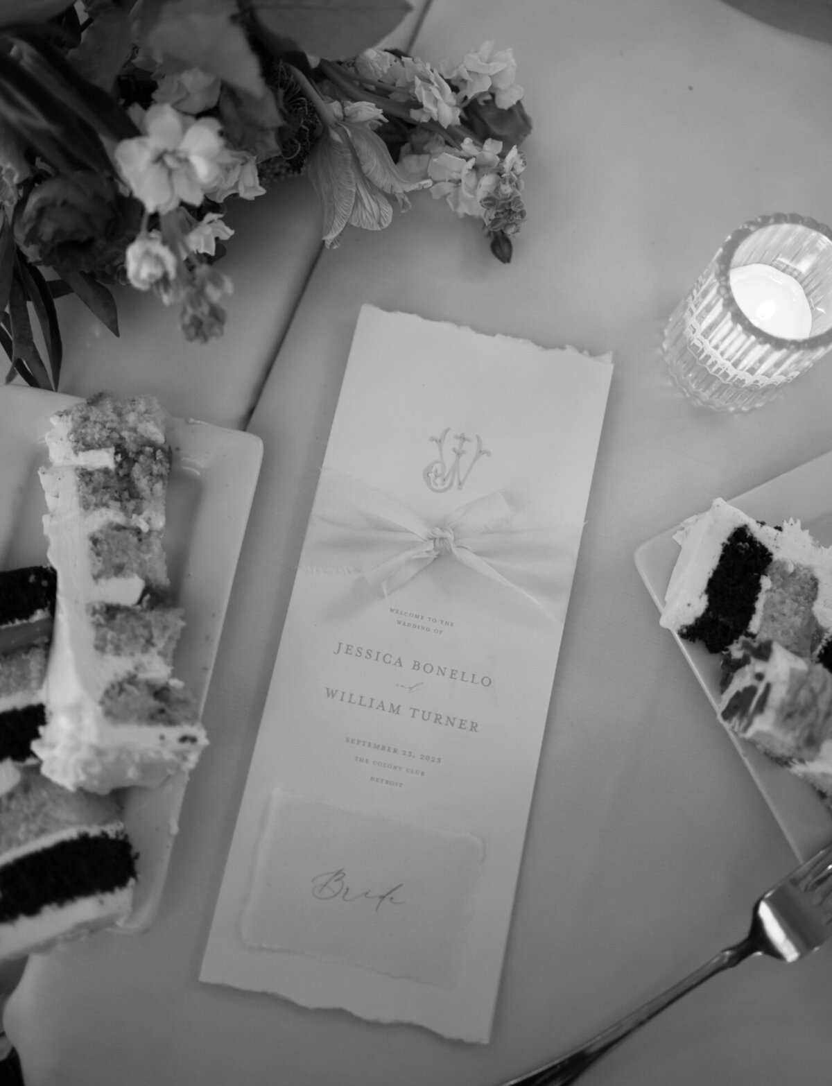 Cut wedding cake, candles, and menu details at a Colony Club Detroit wedding reception 