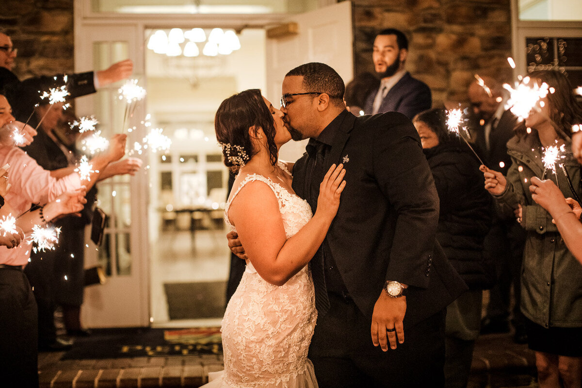 Wedding couple kissing at a sparkler exit