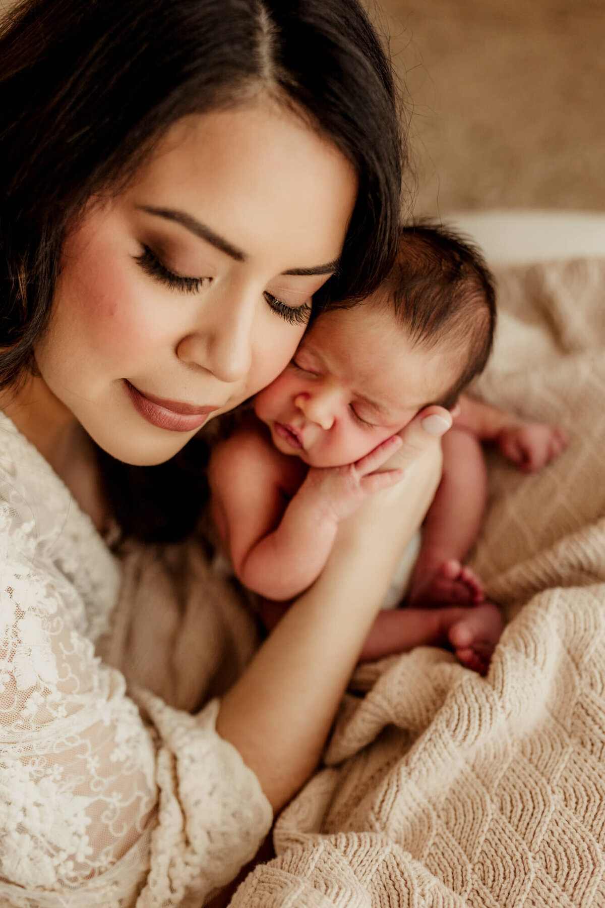 Mother touches her face to her son's face while holding him after burping him, Studio newborn session Yukon, Oklahoma.