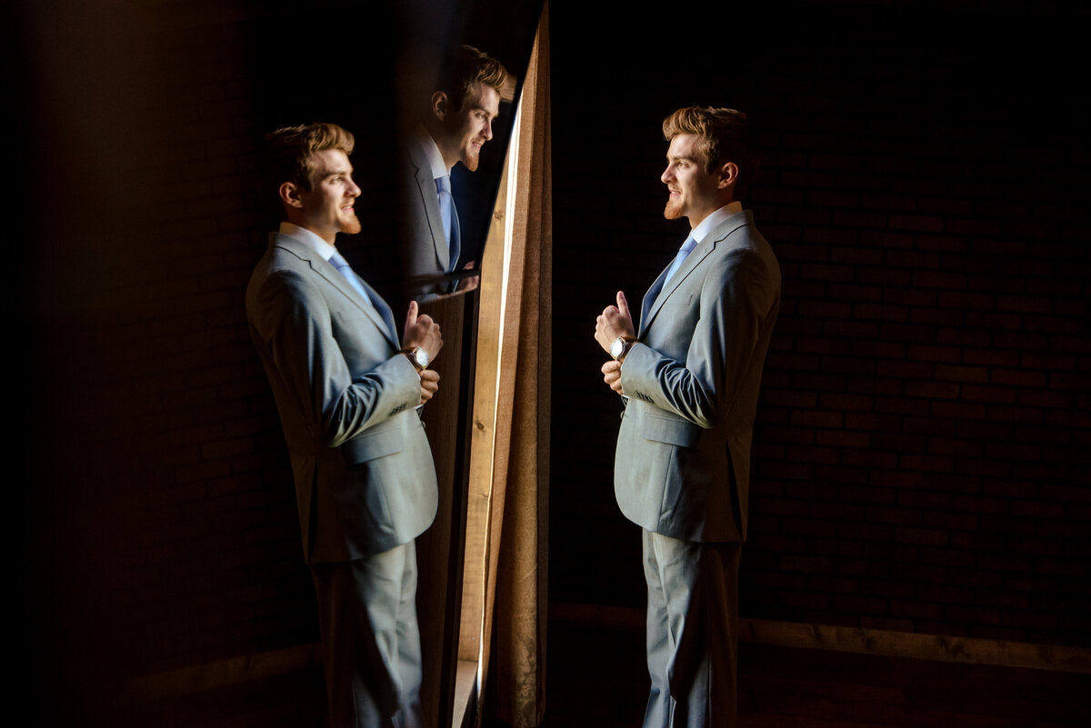 Triple reflection of groom getting ready in groom's suite at Lady Bird Farms by Charlotte wedding photographers DeLong Photography