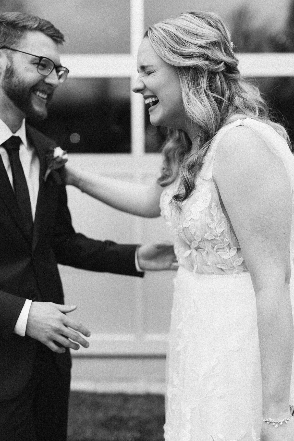 Black and white image of bride and groom laughing