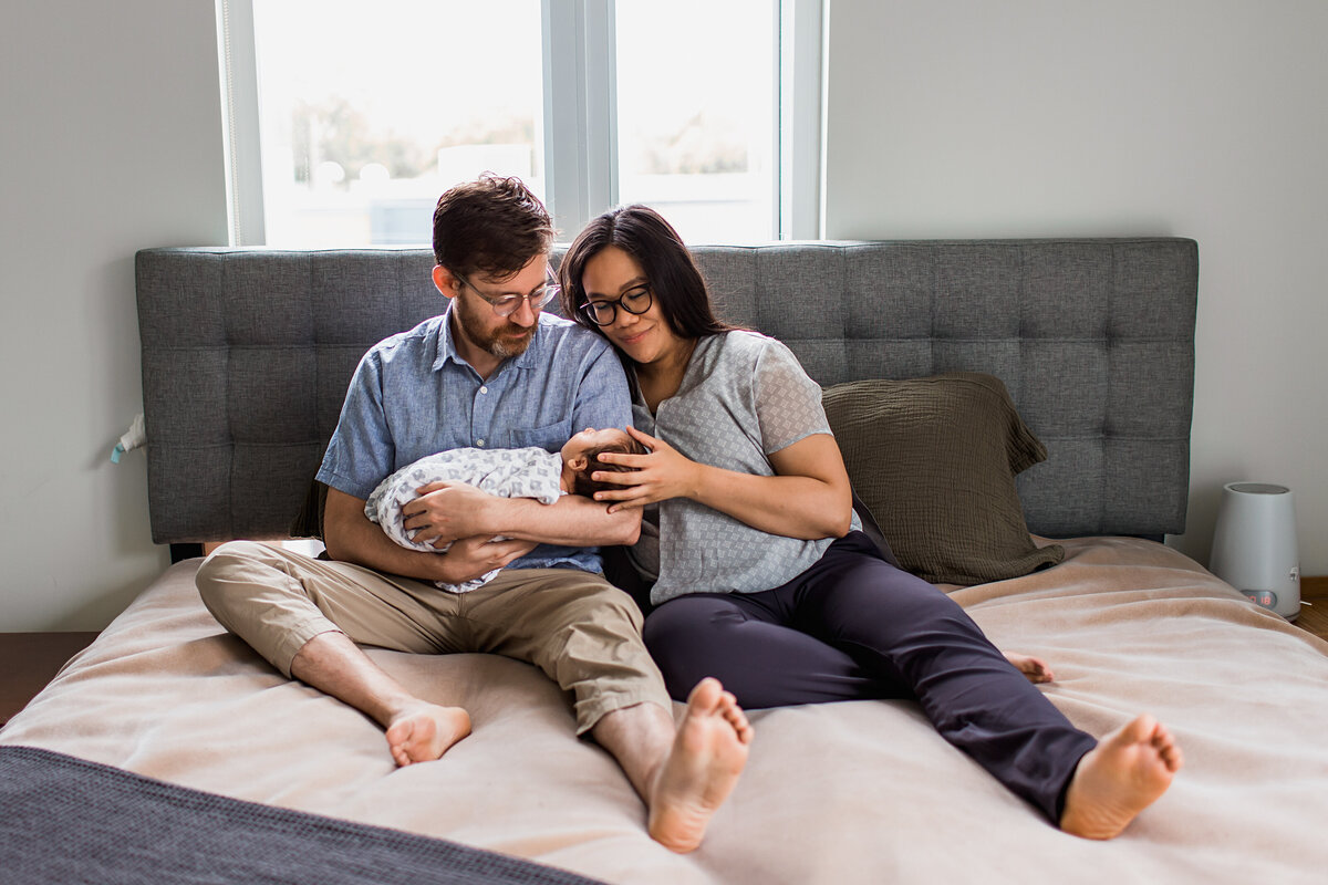 parents on bed with newborn daugther