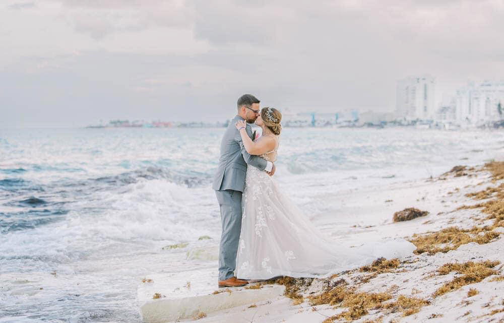 a bride and groom walk on the beach in Cancun