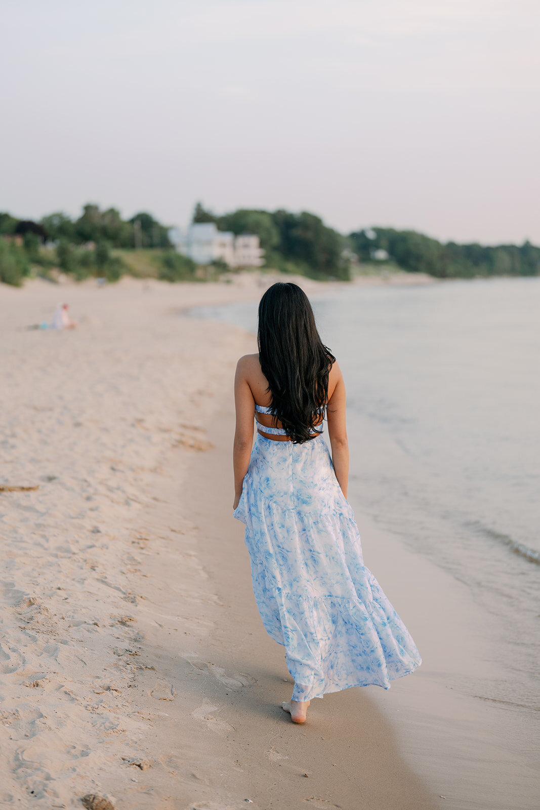 High school senior walking along the shoreline at South Haven North Beach during her Michigan beach senior session.