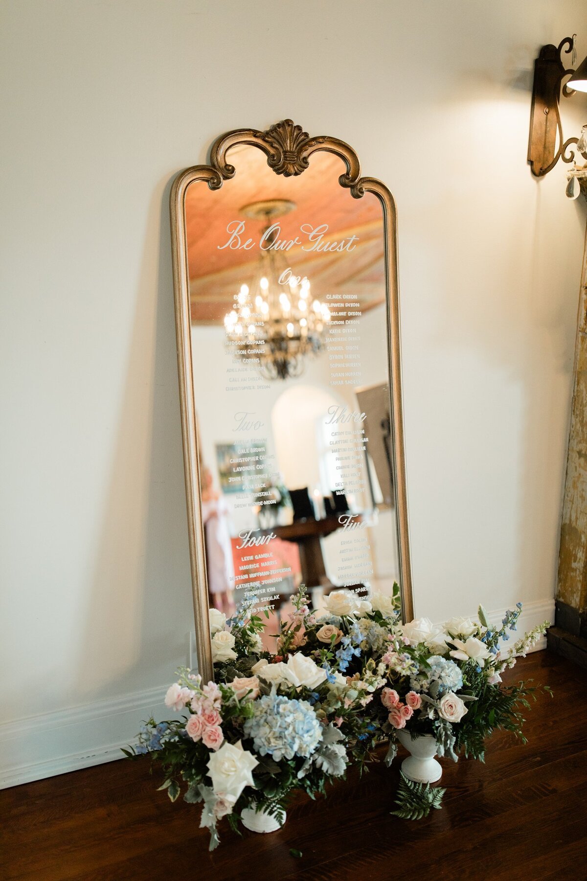 Large gold wood mirror with ornate arches at the top and calligraphy for a seating chart