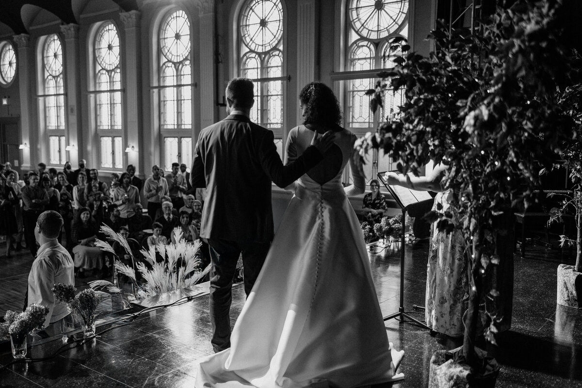 Back view shot of the bride and groom reading their speeches to the guests at the stage