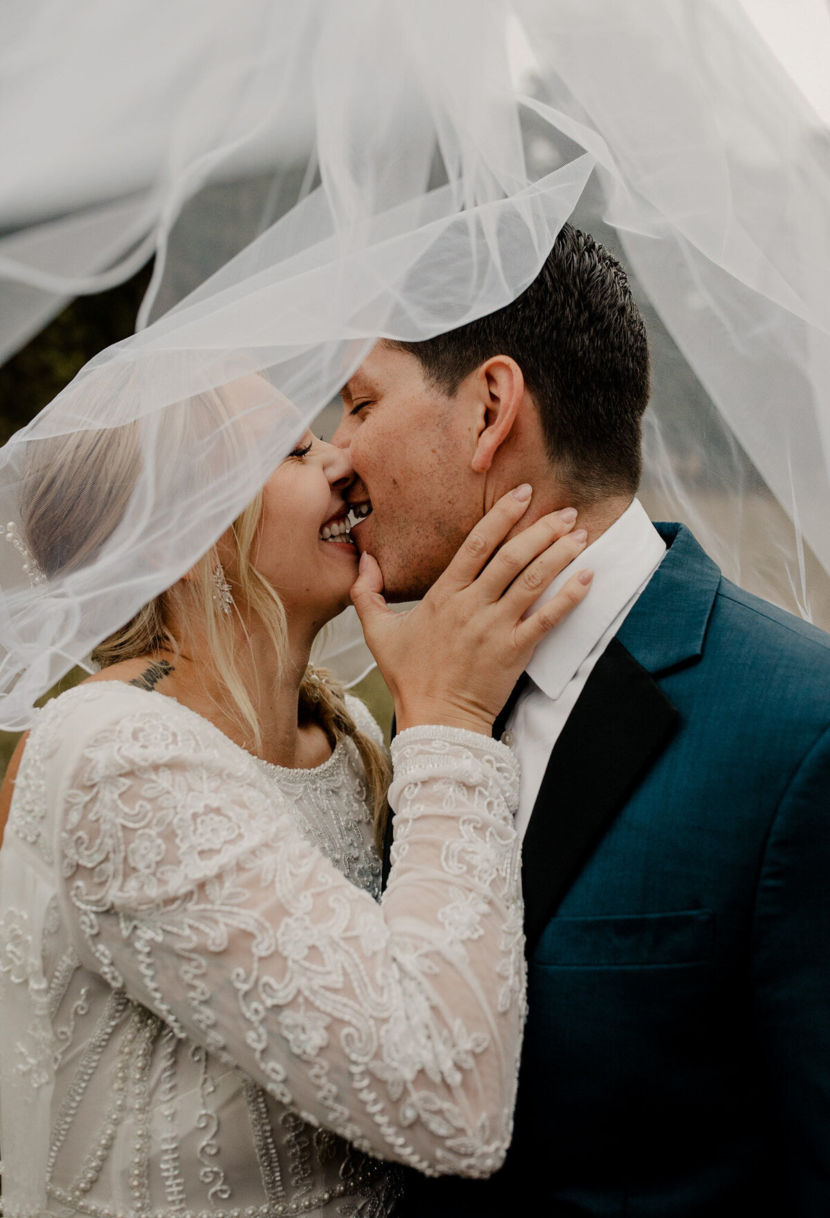 Couple kissing under a veil at their wedding