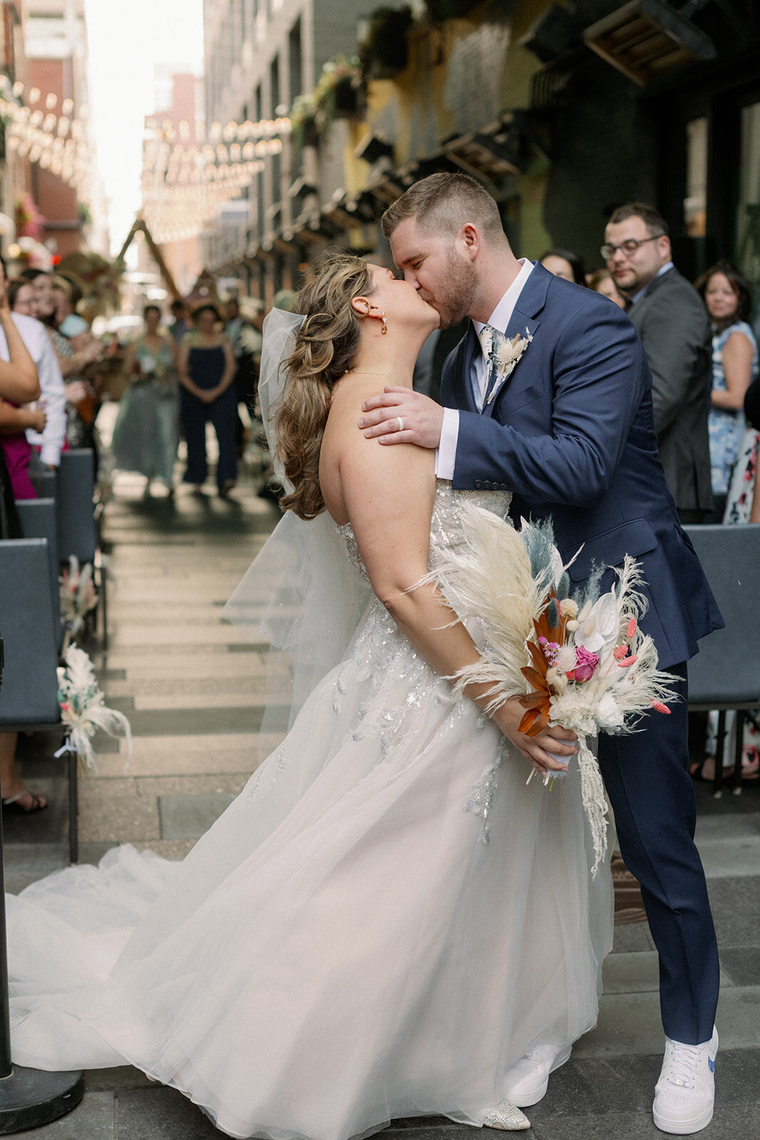 Bride and groom share a kiss on their wedding day with her dried floral bouquet.