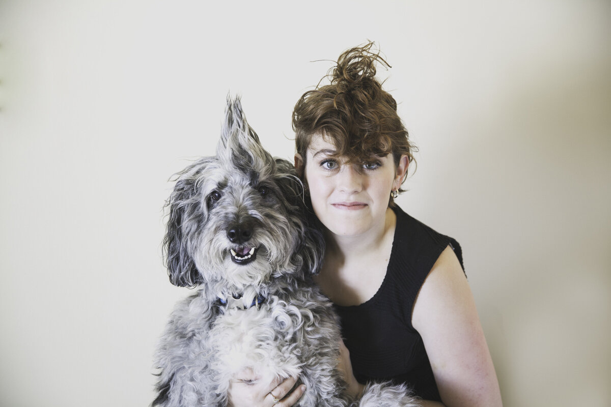 A pet owner  smiles next to their pet, both with matching hair.