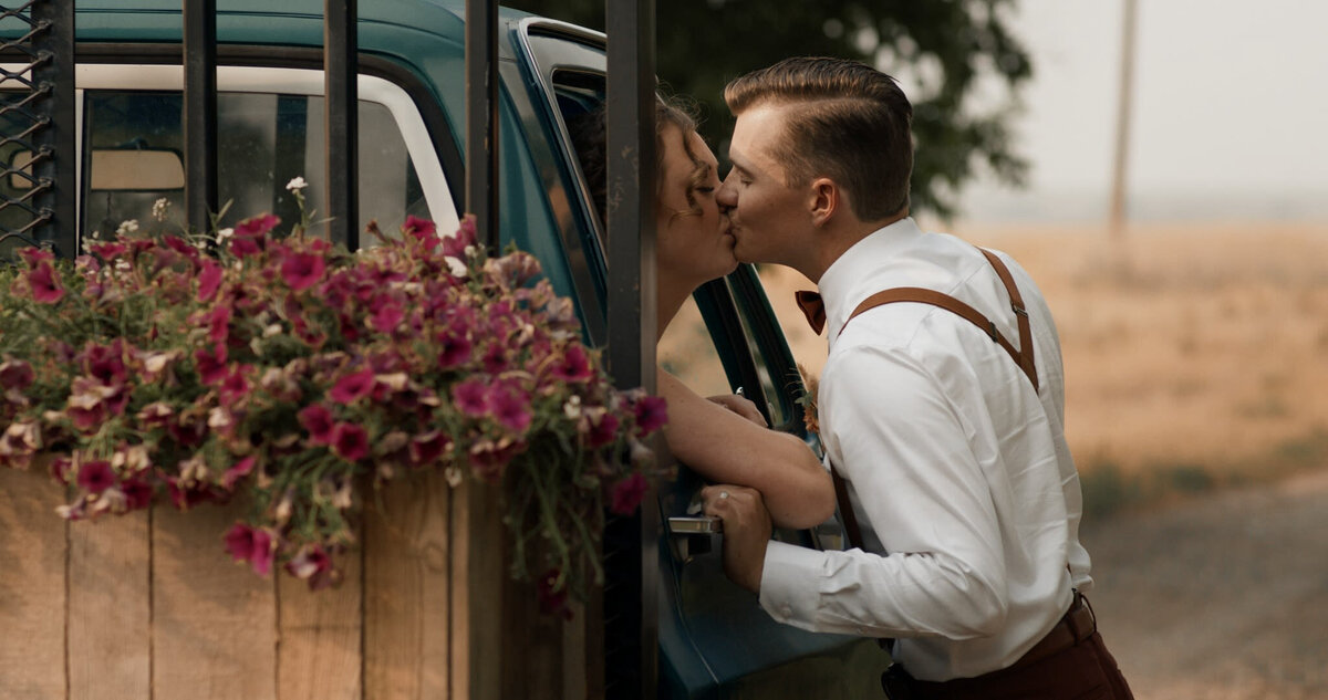 Bride and groom kissing in vintage truck, captured by Prairie Orchid Weddings, wedding videographers in Lethbridge, Alberta. Featured on the Bronte Bride Vendor Guide.