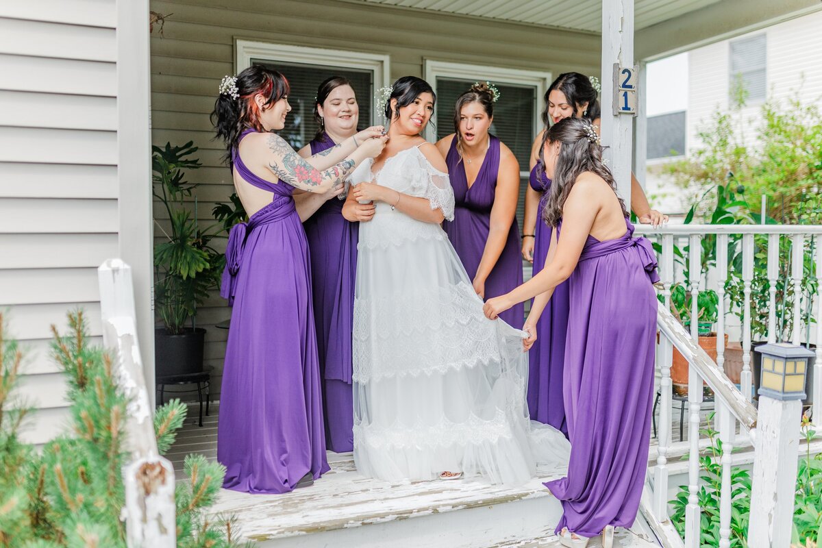 bride with bridesmaids on house porch during wedding photo session in albany ny 