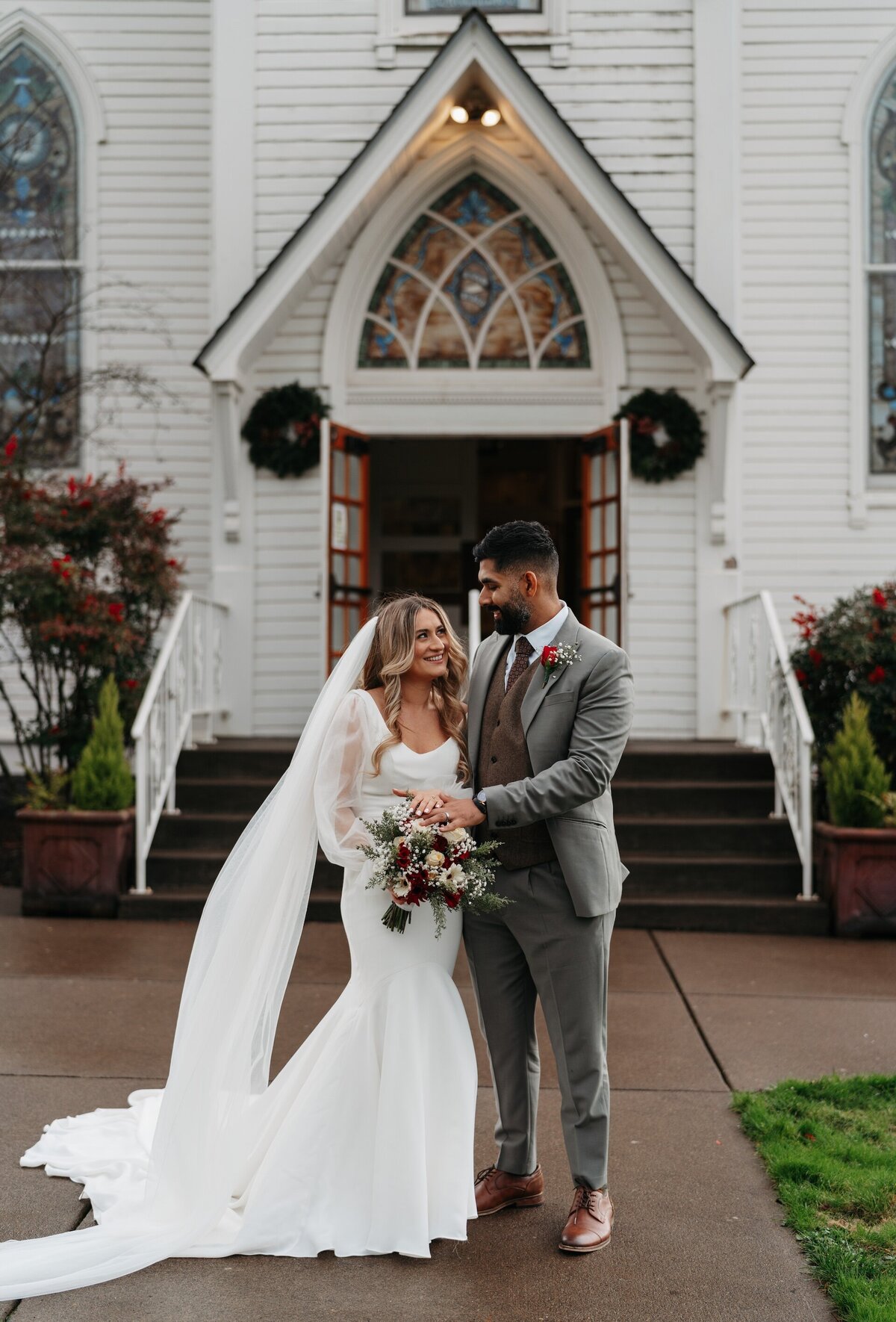 bride and groom smiling outside a church