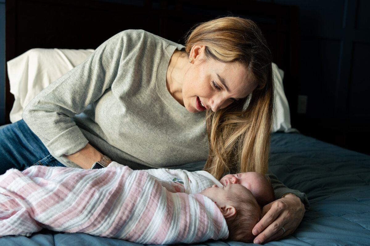 Mom laying on bed looking at newborn daughters