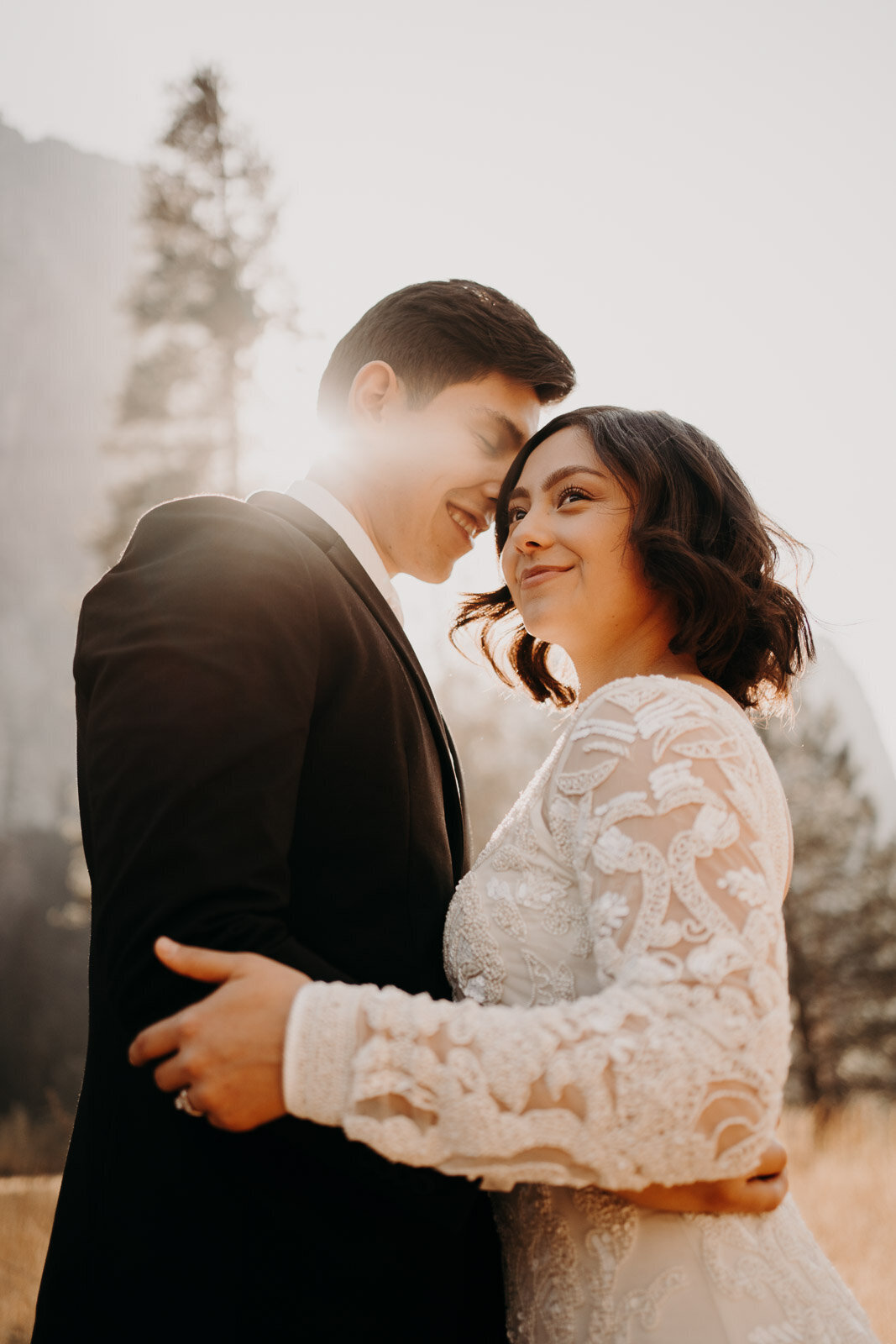 bride & groom embracing each other as the sun shines from behind the grooms head