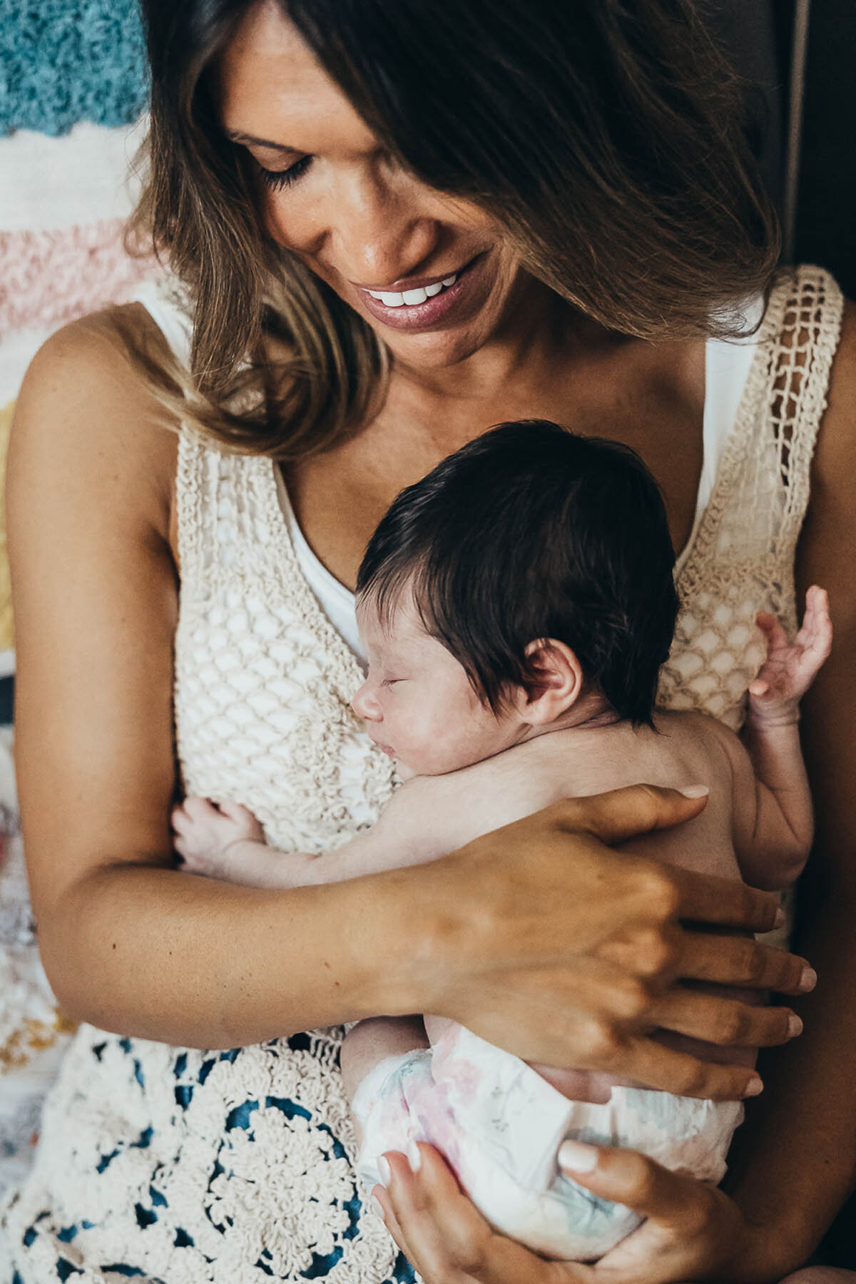 mother holds her newborn baby and looks down at her smiling.