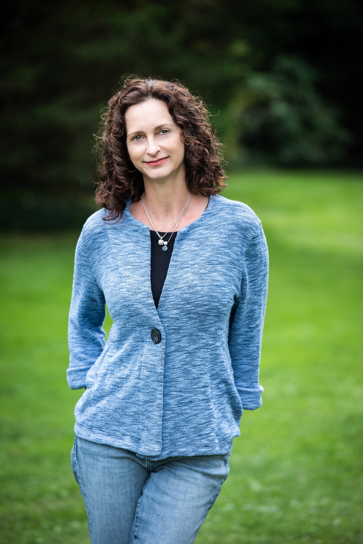 A woman standing outside with her hands in her back pockets