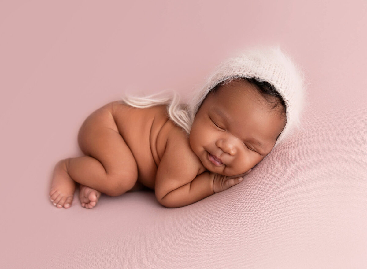 Newborn baby girl laying on a pink blanket naked baby pictures at newborn session Rochel Konik Photography studio in NYC