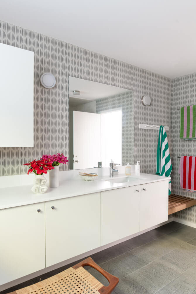 Modern bathroom design in a new construction home in Hingham, Massachusetts, features a white vanity, Schumacher wallpaper, playful towels, and stylish details.