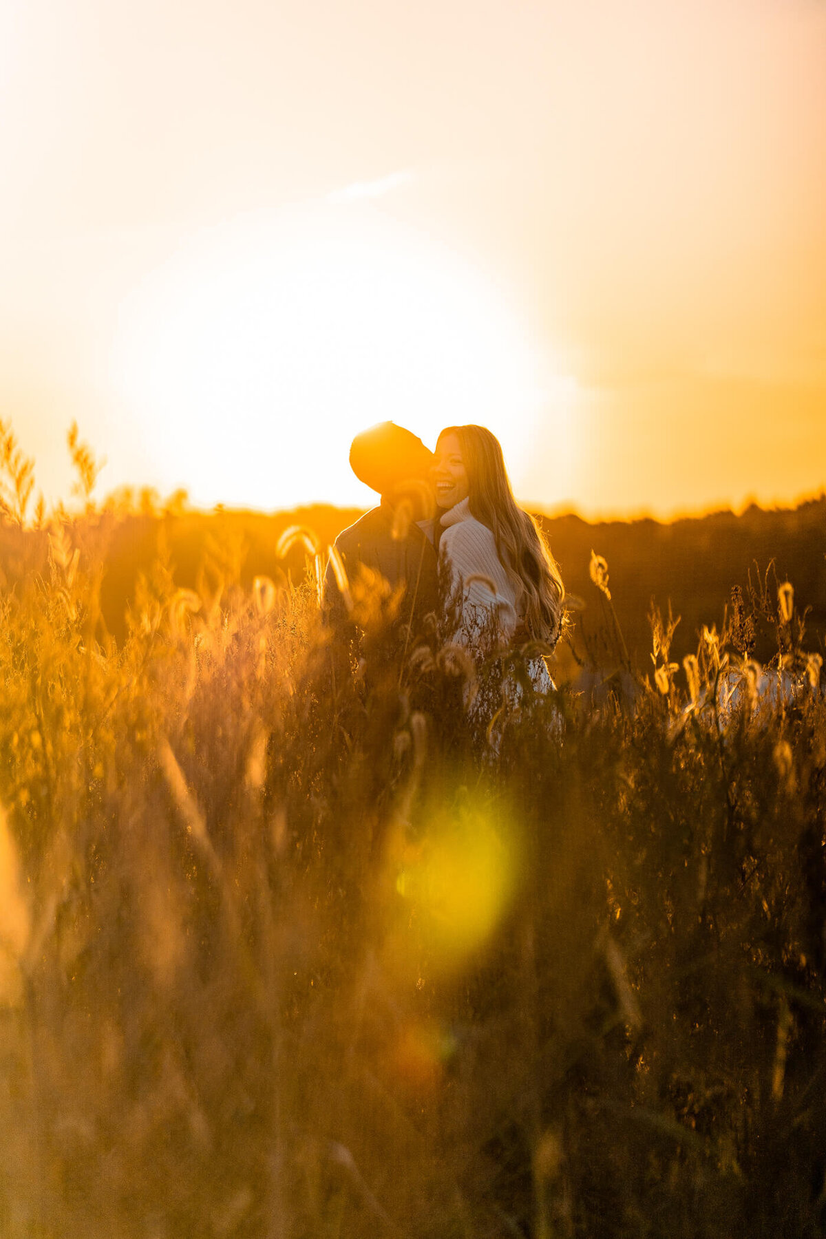 Pittsburgh Engagement photo of a man kissing his fiance on the cheek during a golden sunset in beaver, PA