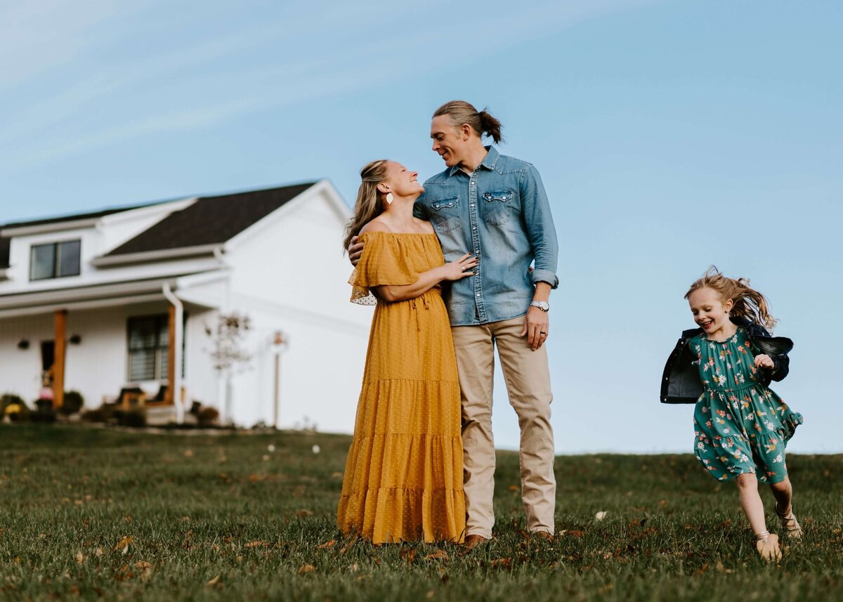 A Pittsburgh family is standing in front of a white farmhouse.