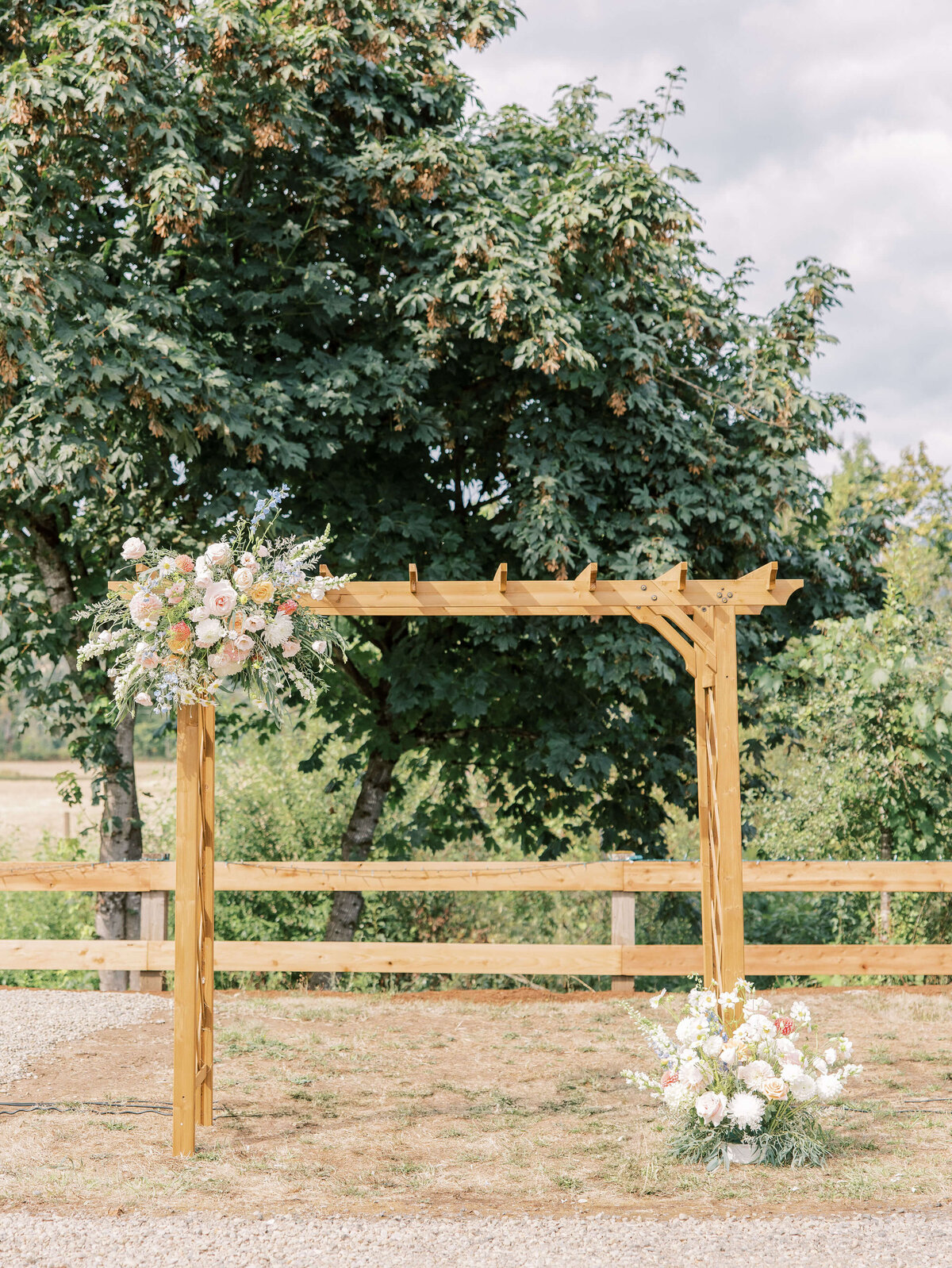 A wooden arbor with a flower installation at a luxury backyard wedding.