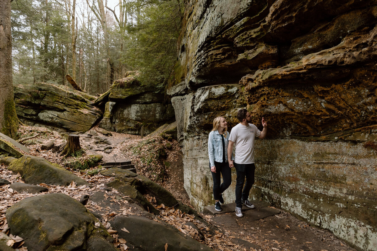 Couple walking under a rocky ledge at Ledges in Cuyahoga Valley National Park.