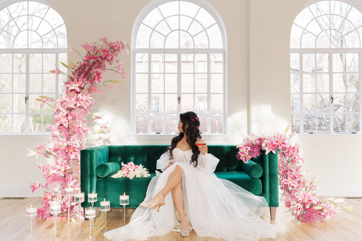 bride sitting on emerald green sofa with pink florals at the hall at safe harbor