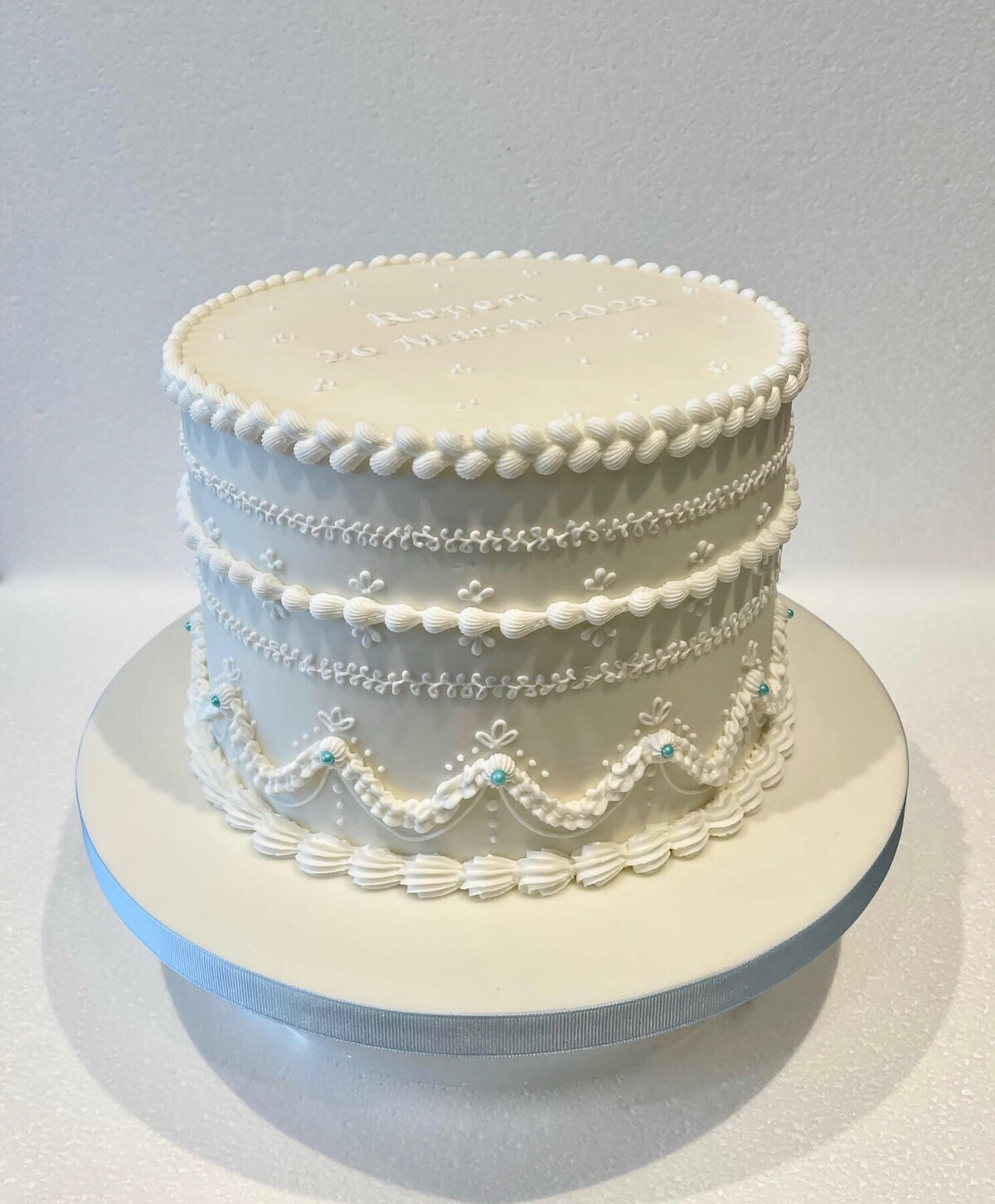 A completely white cake with piped icing designA completely white cake with piped icing design