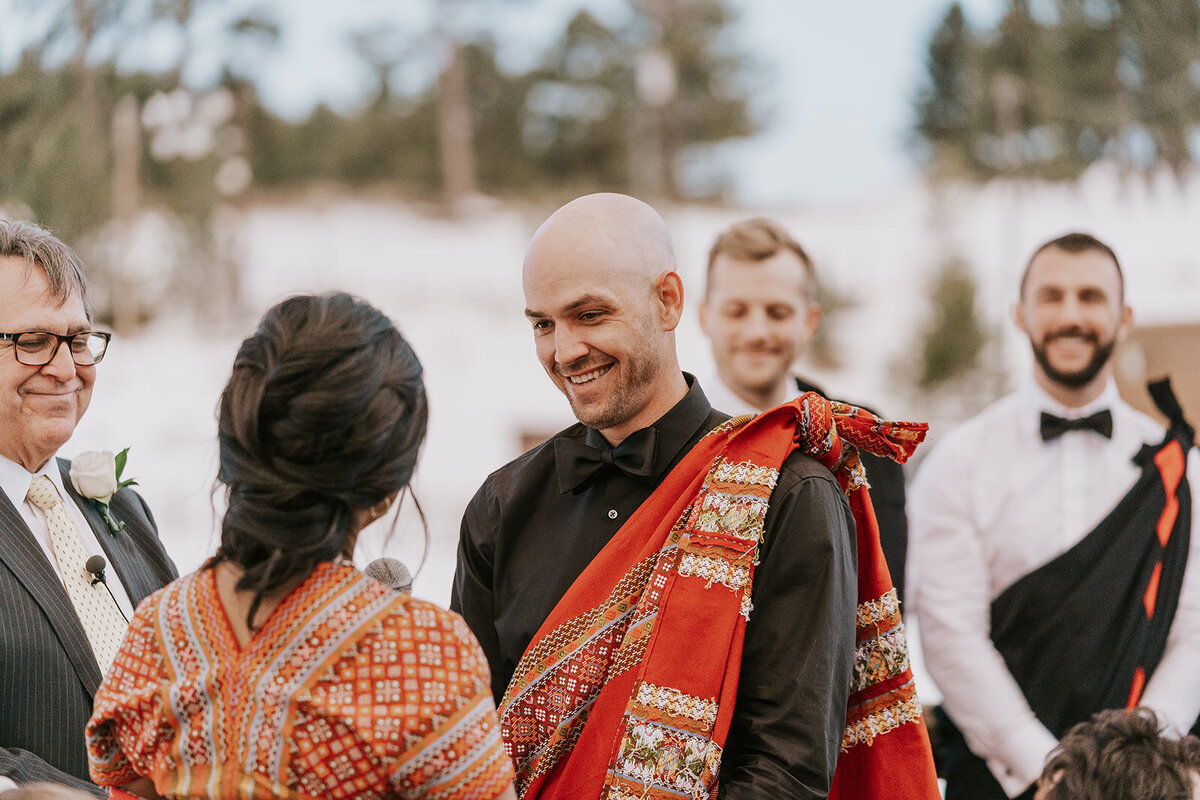 Groom smiles at his bride during their wedding ceremony.