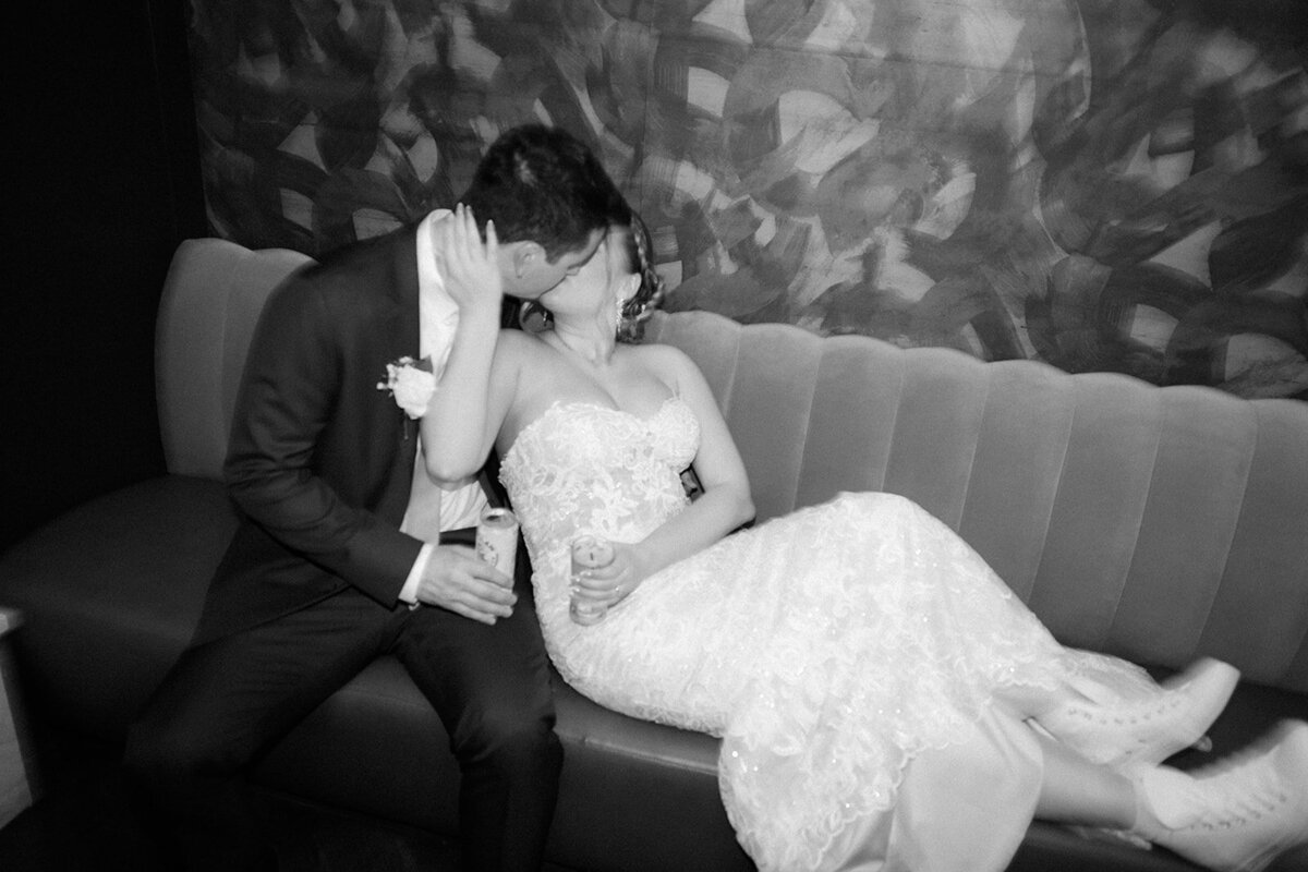 Couple sitting on vintage couch with champagne glasses after their ceremony.