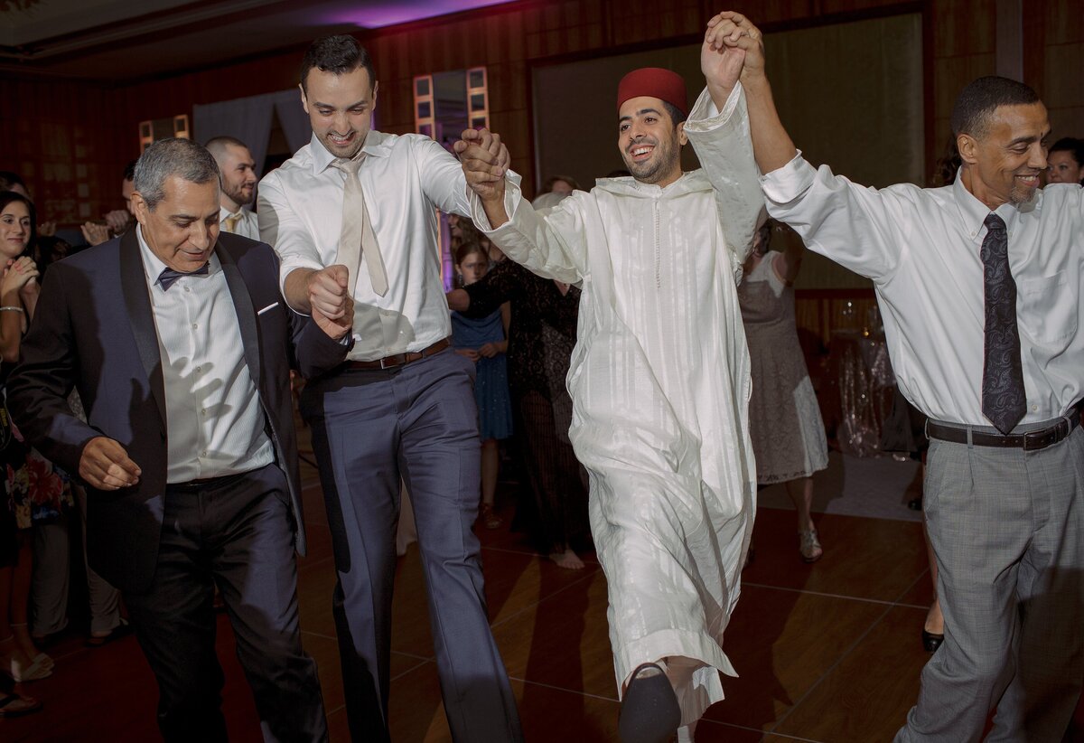 Groom dances with guests in traditional Moroccan wedding attire.