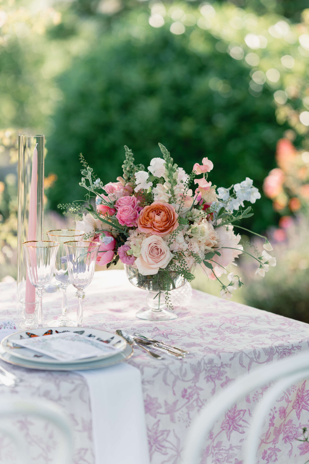 a wedding table with pink and white floral linen featuring a bouquet of summer flowers in shades of pink for a wedding at euridge manor in the cotswolds
