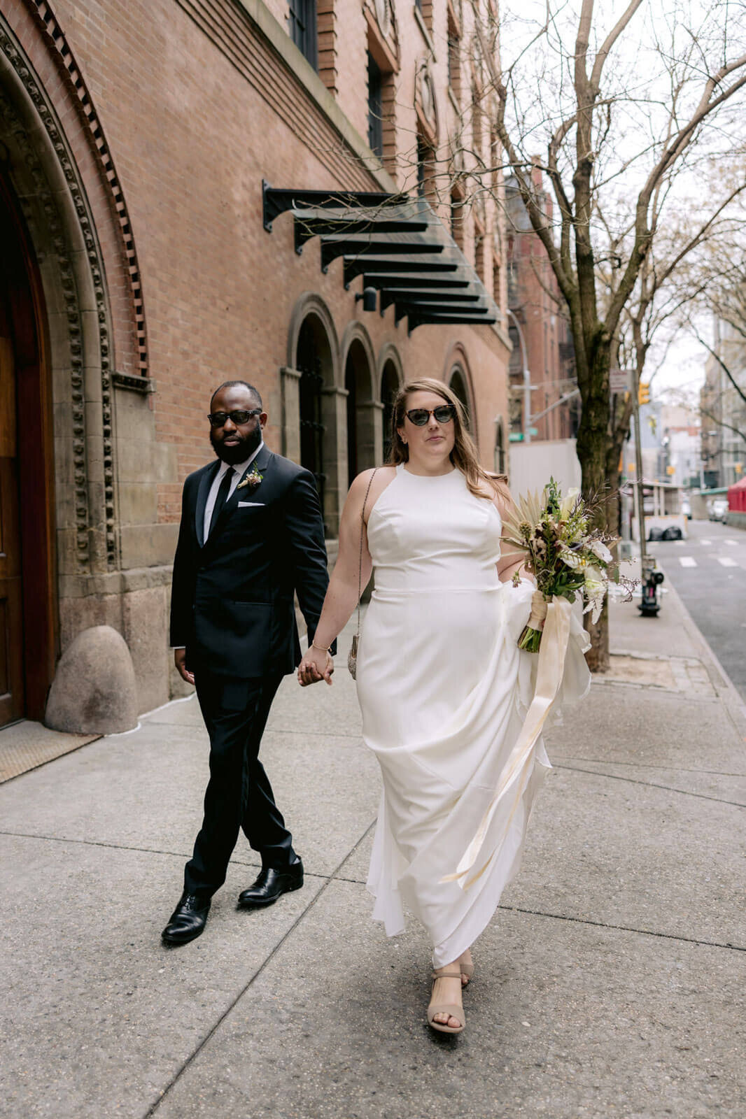 The bride and the groom are walking in the streets of New York City.