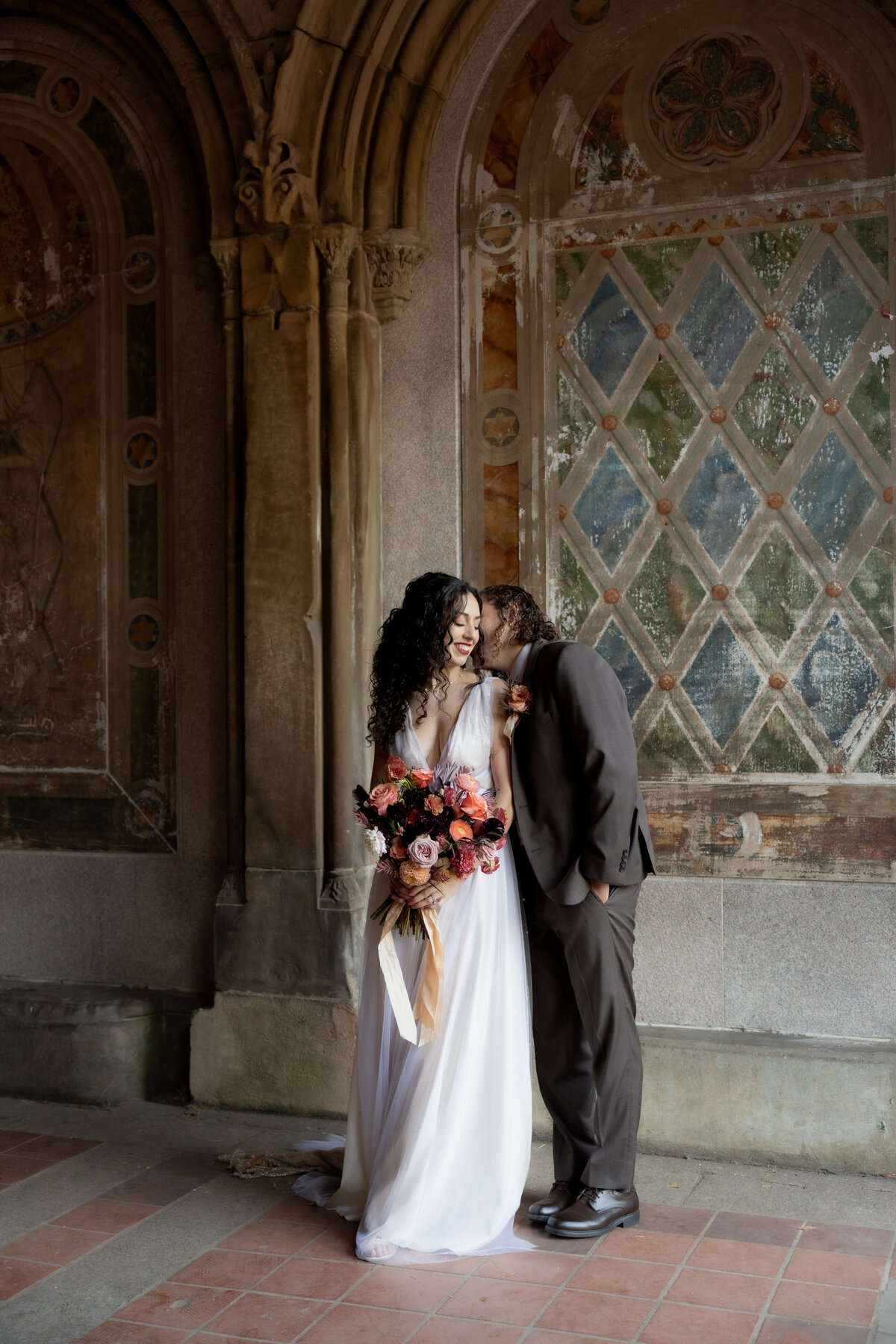 The couple sharing a tender moment beneath Central Park’s beautiful stone arches.