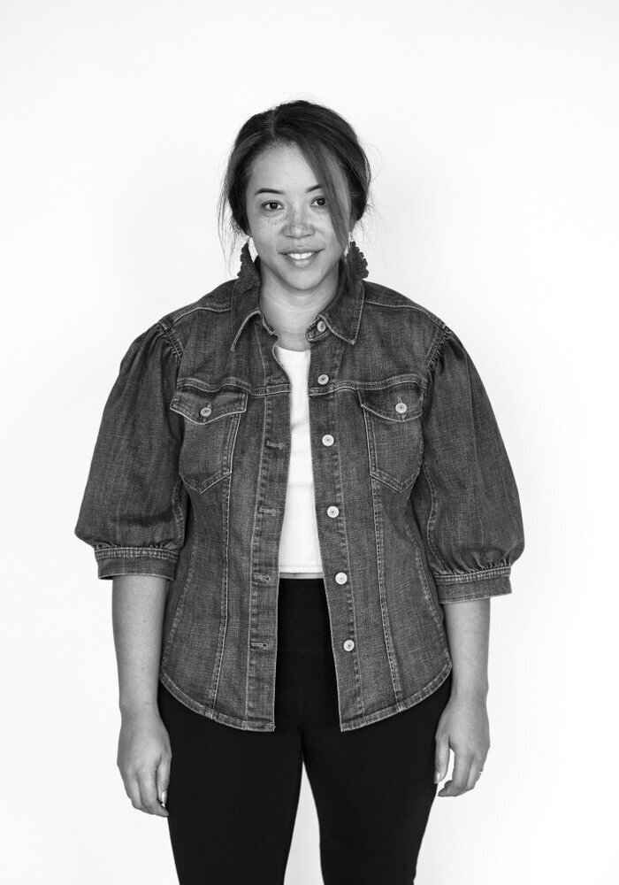 Before shot of a woman in a denim jacket and white shirt, smiling gently with a welcoming expression.