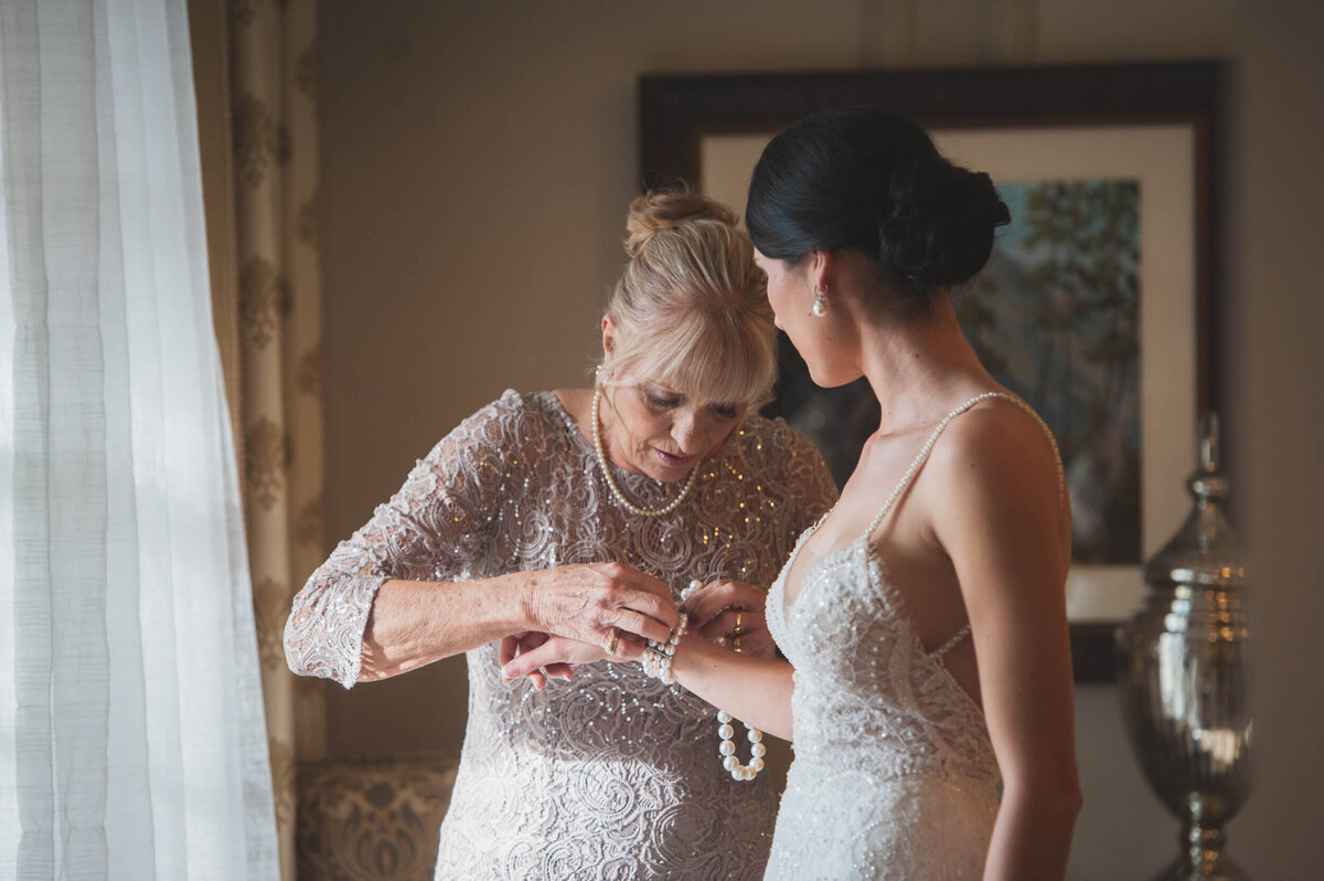 Mother of the bride helping her daughter put on her diamond bracelet