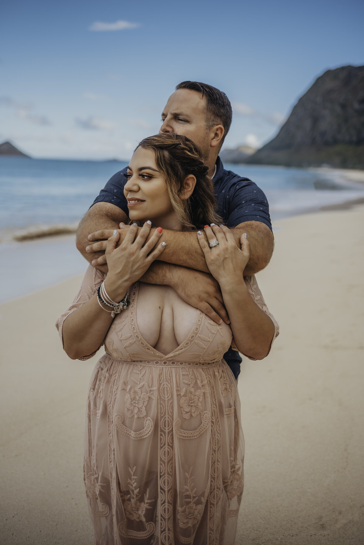 Man holding woman across her chest on beach