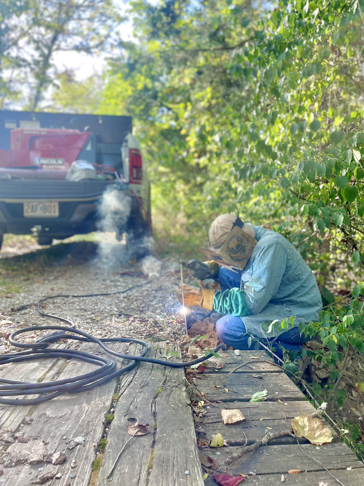 Certified welder performing field welding on-site with mobile welding truck and equipment for structural steel repair.