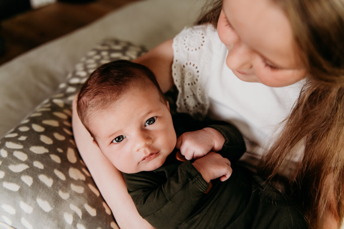 Newborn Photographer, Big sister holding baby brother on the couch.