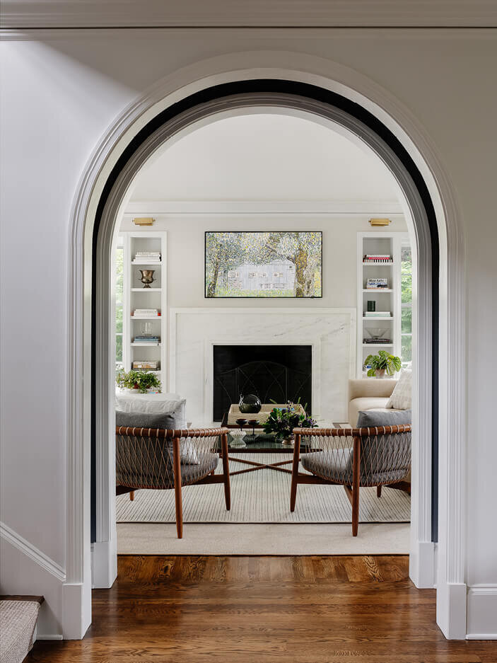 Arched opening into a formal living room at a historic home renovation project in Hingham, designed by Boston interior designers, blending classic and modern style.