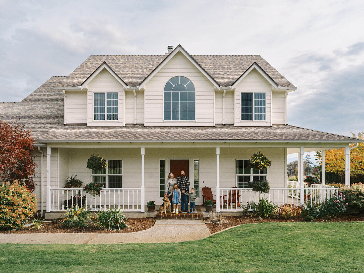 A family standing on the front porch of their house.
