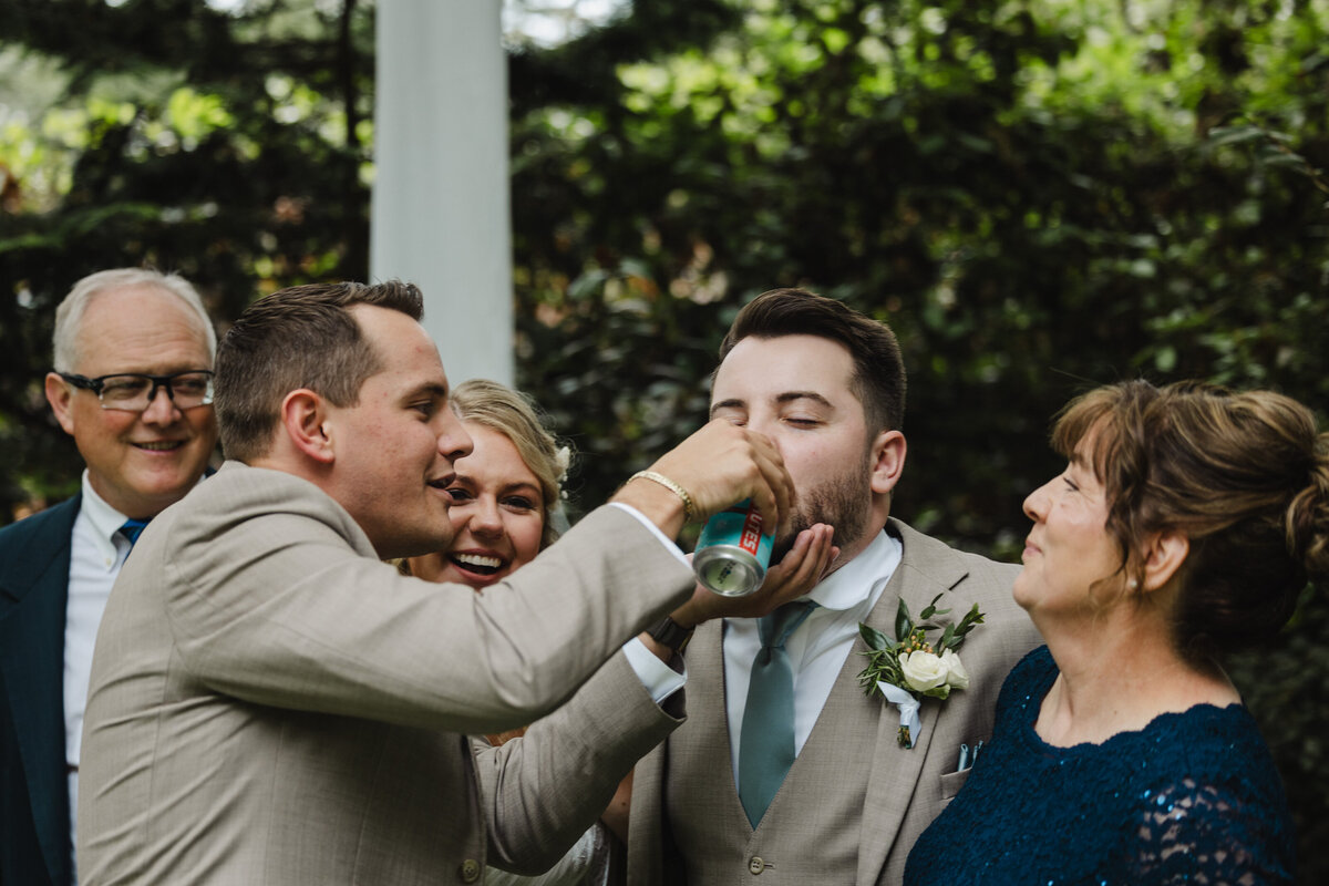 A person holding a can up to another person's mouth as they drink