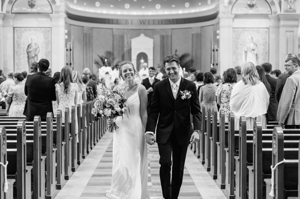 Bride and groom walking down ceremony aisle smiling