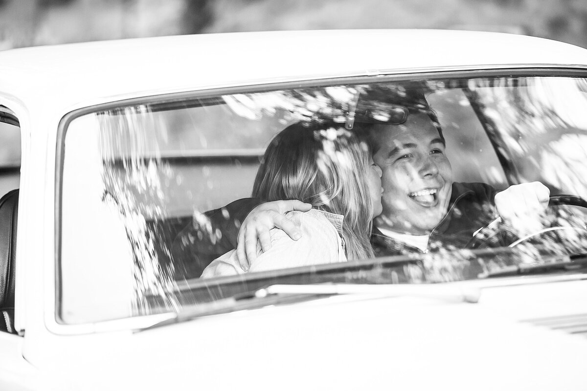 A bride kisses her groom in a vintage car.
